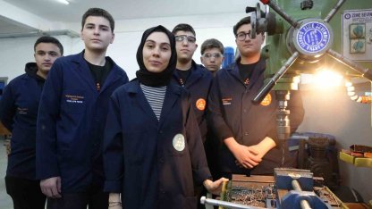 Kadın öğretmen torna tezgahında öğrencilerine üretimi öğretiyor